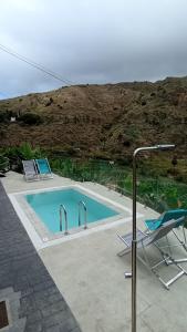 a swimming pool with two chairs and a table and a lamp at VV Casa Bibiana "by henrypole home" in Hermigua