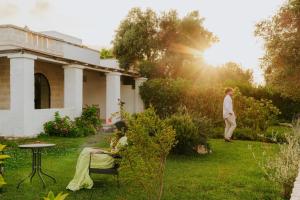 una mujer sentada en una silla en el patio de una casa en Masseria della Piana, en Villanova di Ostuni