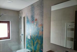 a bathroom with a shower and a mosaic wall at Sporthotel Olimpo in Garda