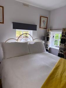 um quarto com uma cama com lençóis brancos e uma janela em Rathjarney Gatelodge em Wexford