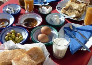 una mesa cubierta con platos de comida, huevos y pan en La Vallée des Dunes - Auberge, bivouacs et excursions en Merzouga