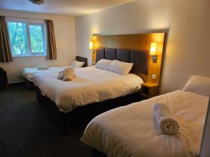 Habitación de hotel con 2 camas con sábanas blancas en V Lodge Manchester en Mánchester