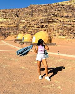 a woman standing in the desert holding an umbrella at Wadi Rum Classic camp in Aqaba