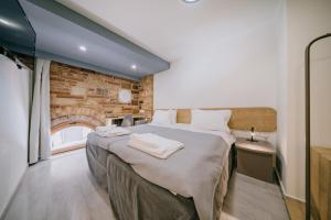 1 dormitorio con 1 cama grande y pared de ladrillo en Chios City Inn en Chios
