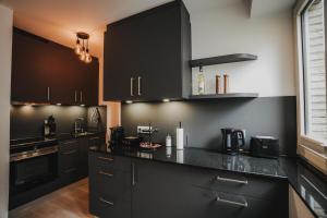 eine Küche mit schwarzen Schränken und einer schwarzen Arbeitsplatte in der Unterkunft DOWNTOWN Apartment mit Luxusbad am Hafen nur 5 Minuten zu Fuß in die Innenstadt und zum Bahnhof! in Oldenburg