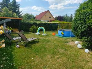 a yard with two chairs and an umbrella and a playground at Ferienwohnung mit großem Garten in Jesewitz