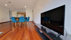 a living room with a flat screen tv and blue chairs at Capela's House in Ribeira Brava