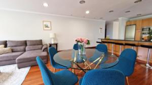 a living room with a glass table and blue chairs at Capela's House in Ribeira Brava