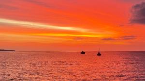 dwie łodzie w oceanie o zachodzie słońca w obiekcie Izu Hokkawa Seaside Guesthouse 伊豆北川の家 w mieście Higashiizu