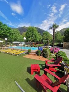 a group of red chairs and a swimming pool at Camping Melezza in Losone