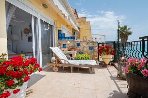 d'une terrasse avec une chaise et des fleurs sur un balcon. dans l'établissement Poseidon Seafront Apartment by RentalsPro - Siviri Halkidiki, à Siviri 44 autres photos