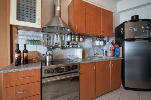 une cuisine avec des armoires en bois et un réfrigérateur en acier inoxydable dans l'établissement Poseidon Seafront Apartment by RentalsPro - Siviri Halkidiki, à Siviri