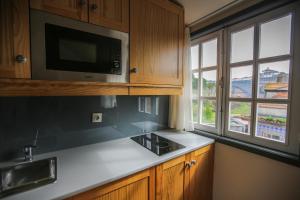 cocina con fregadero, microondas y ventanas en My Ribeira Guest House, en Oporto