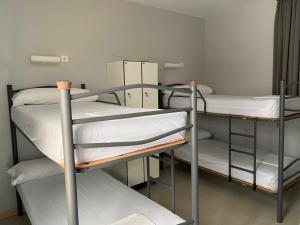 Zimmer mit 3 Etagenbetten mit weißer Bettwäsche in der Unterkunft Albergue de Villava in Villava