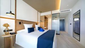 um quarto com uma grande cama branca e um cobertor azul em H10 Costa Mogán em Playa del Cura