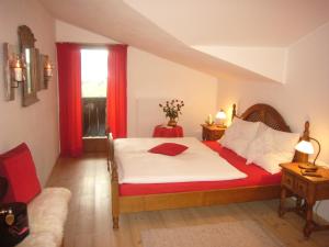 Schlafzimmer mit einem Bett und einem Fenster mit roten Vorhängen in der Unterkunft Das Sonneck in Mühlbach am Hochkönig
