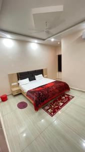 a bedroom with a large bed with a red blanket at The Ramagya Hotel, Chitrakoot in Sītāpur Mūāfi