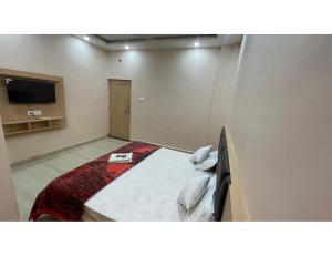 um quarto de hotel com uma cama e uma televisão de ecrã plano em The Ramagya Hotel, Chitrakoot em Sītāpur Mūāfi