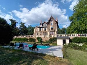 una casa vieja con una piscina delante en Manoir des Rêves Sauvages, en Parentignat