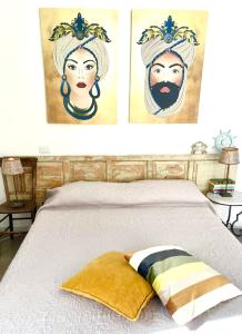a bed with three paintings of a man and a woman at EcoCasa Neapolis in Siracusa