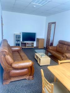 sala de estar con muebles de cuero y TV de pantalla plana en Turnė en Šiauliai