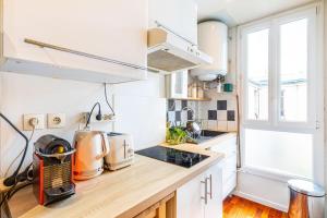 a kitchen with white cabinets and a wooden counter top at GuestReady - Vibrant landscape in the 19th arr. in Paris