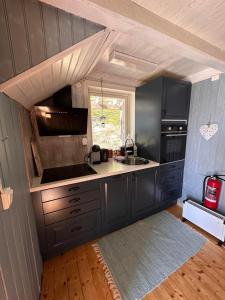 a kitchen with black cabinets and a sink and a window at Moskenes Cabin in Moskenes