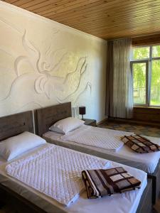 two beds in a room with a wall with a mural at GRIGOLETI River Club in Grigoleti