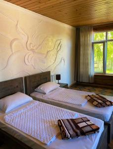 two beds in a bedroom with a wall with a mural at GRIGOLETI River Club in Grigoleti