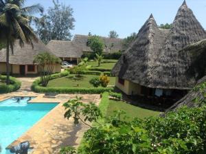 a resort with a swimming pool and a thatch roof at Malaika Holiday Villas in Diani Beach