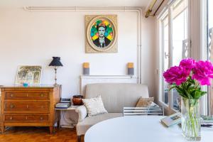 ein Wohnzimmer mit einem Stuhl und einer Vase aus rosa Blumen in der Unterkunft GuestReady - Flor de solstício de verão no 12º arr. in Paris
