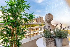 eine Statue auf einem Balkon mit Pflanzen in der Unterkunft GuestReady - Flor de solstício de verão no 12º arr. in Paris
