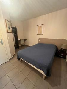 - une chambre avec un lit et une couverture bleue dans l'établissement Hôtel Le Juliano, à Carbon-Blanc