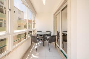 シャルネカにあるGuestReady - Caparica Beach Lover's Dreamのバルコニー(テーブル、椅子付)、窓