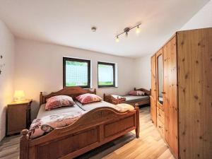 a bedroom with a large bed and two windows at Apartment Ferienapartments Adenau-1 by Interhome in Adenau