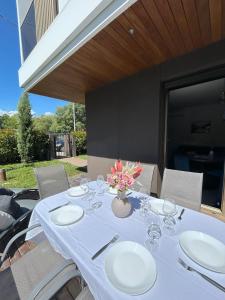 una mesa con platos y vasos y un jarrón con flores en Cortemaggiore 4B Luxury-Flexrent Abissinia, en Riccione