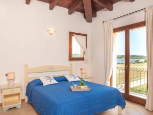 1 dormitorio con cama azul y balcón en Apartment I Mirti di Porto Pozzo - PPZ122 by Interhome, en Porto Pozzo