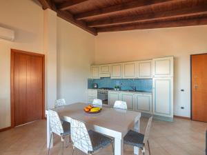 cocina con mesa y sillas y cocina con armarios azules en Apartment I Mirti di Porto Pozzo - PPZ122 by Interhome, en Porto Pozzo