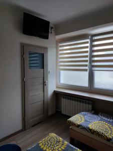a bedroom with windows and a bed and a television at Kwatery Rydz in Częstochowa