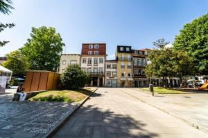 a person sitting on a bench on a street with buildings at On The Square Flat - City Center by House and People in Braga