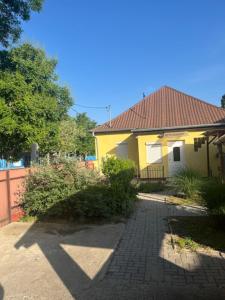 żółty dom z ceglanym chodnikiem przed nim w obiekcie Dyta2 apartman w Hajduszoboszlo