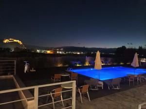 a swimming pool at night with chairs and umbrellas at Palacio del Sol Luxury Apartments in Nafplio