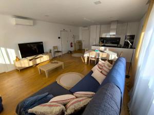 a living room with a blue couch and a kitchen at Full Nathur I Central Ericeira in Ericeira
