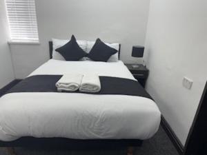 1 dormitorio con 1 cama grande con almohadas blancas y negras en The Firs Lodge, en Hounslow