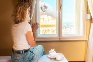 奧帕蒂亞的住宿－BRISTOL Hotel Opatija，坐在床上,从窗户望出去的女人