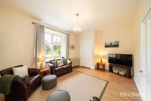 a living room with a couch and a television at Station Cottage Dinnet, Aboyne in Aboyne