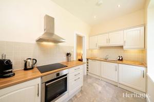 a kitchen with white cabinets and a stove top oven at Station Cottage Dinnet, Aboyne in Aboyne