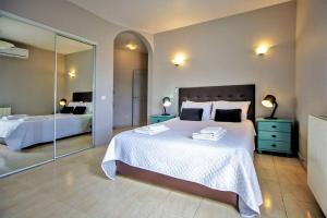 een slaapkamer met een groot wit bed en een spiegel bij Vila Ventura Marina in Albufeira