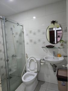 uma casa de banho com um WC, um lavatório e um espelho. em VANAPARTMENT em Ho Chi Minh