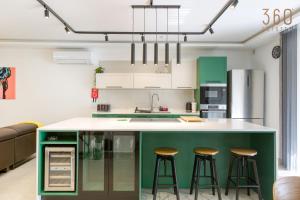 马尔萨斯卡拉Designer 3BR home in charming Marsascala by 360 Estates的一个带酒吧凳子的绿色岛屿的厨房